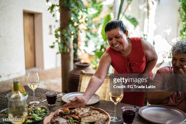 mujer madura sirviendo tabla de charcutería con pan y verduras - antipasto fotografías e imágenes de stock
