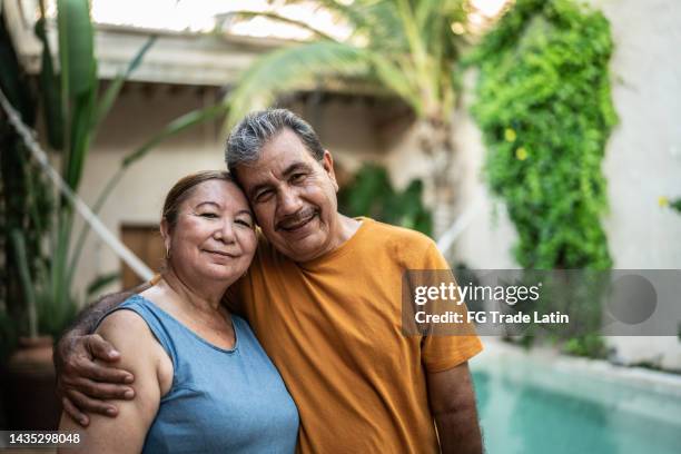 portrait of mature couple embracing by the pool - mature latin women stockfoto's en -beelden