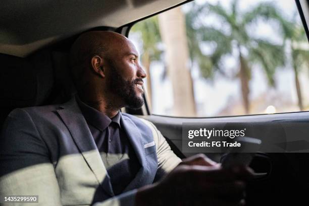 mid adult man looking through the window in a car - project traveller stock pictures, royalty-free photos & images