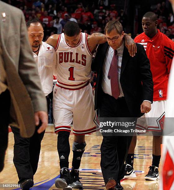 The Chicago Bulls' Derrick Rose is helped off the court by trainers Jeff Tanaka, left, and Fred Tedeschi after he was injured late in the game...