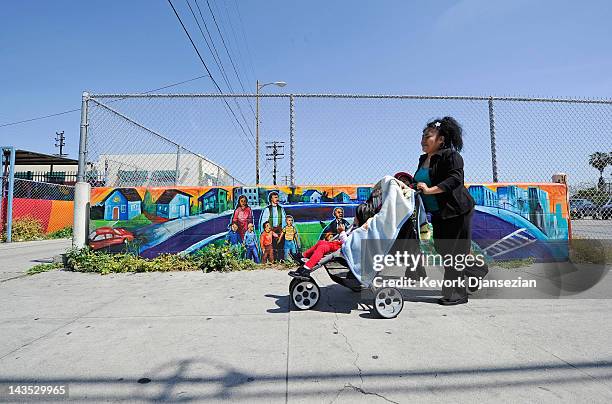 Hispanic family walks past a mural near Vermont Avenue in South Los Angeles on April 28, 2012 in Los Angeles, California. It's been 20 years since...