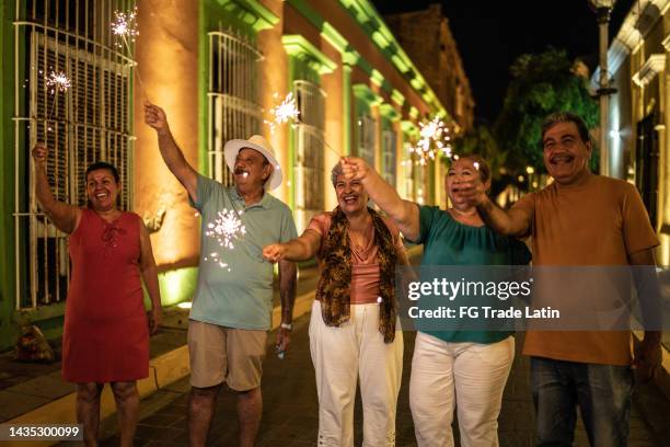ältere freunde feiern silvester mit bengalischen lichtern im historischen viertel - alter wunsch fürs neue jahr stock-fotos und bilder