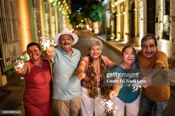 retrato de amigos seniores celebrando o ano novo com luzes de bengala no distrito histórico - bengal new year - fotografias e filmes do acervo