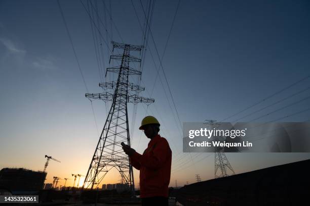 workers in helmets and standard safety uniforms inspect high-voltage power lines. - electricity pylon stock pictures, royalty-free photos & images