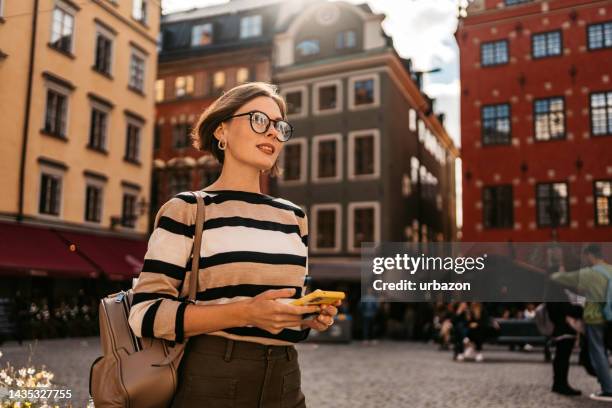 junge frau telefoniert auf der straße in stockholm - stockholm summer stock-fotos und bilder