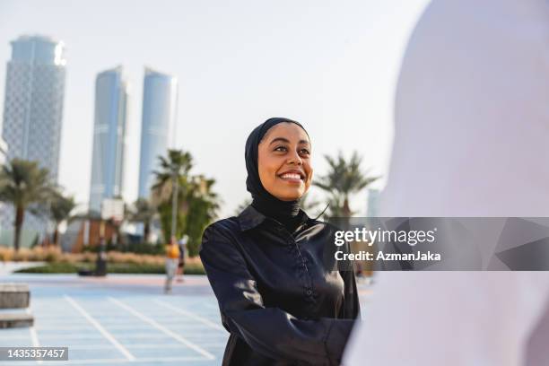 eine junge geschäftsfrau aus dem nahen osten, die draußen in dubai die hände schüttelt - emirati at work stock-fotos und bilder