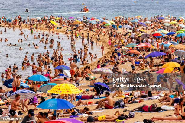 crowds of tourist on barceloneta beach, barcelona, spain - touristen photos et images de collection