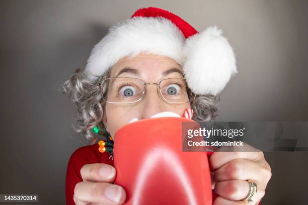 woman sipping ot chocolate at christmas time - mrs claus stock pictures, royalty-free photos & images