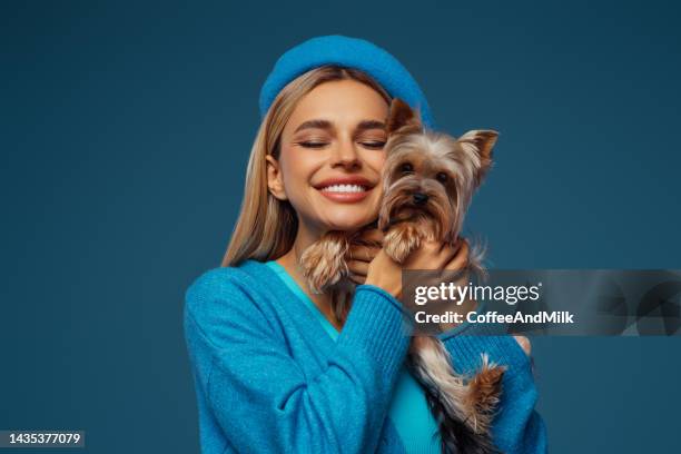 studio-porträt von lächelnden jungen frau hält kleinen hund - woman holding dog studio stock-fotos und bilder