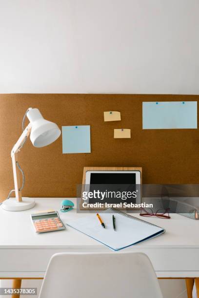 front view image of a study area in a girl's or teenager's room with a desk with study material for homework, and a cork board with map. - homework table stock pictures, royalty-free photos & images