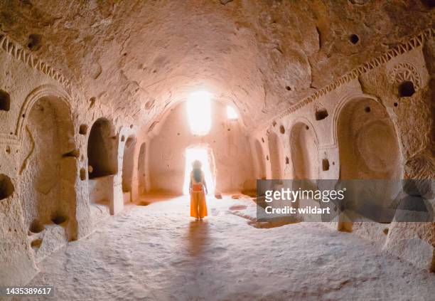 traveler young girl is walking inside a cave church in zelve ancient city at cappadocia in nevsehir , turkey - cappadocië stockfoto's en -beelden