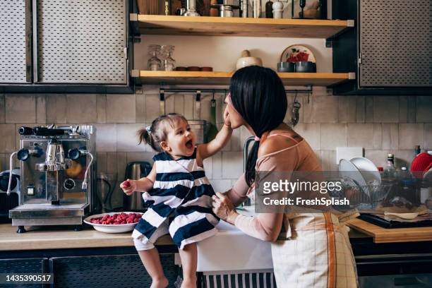 daughter feeding her mother raspberries - sisters feeding stock pictures, royalty-free photos & images