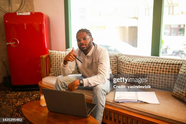 black male student studying with computer in cafe making check mark with his hand - eskisehir stock pictures, royalty-free photos & images