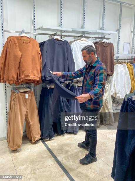 hombre eligiendo ropa para comprar en tienda de ropa - fashion showroom fotografías e imágenes de stock