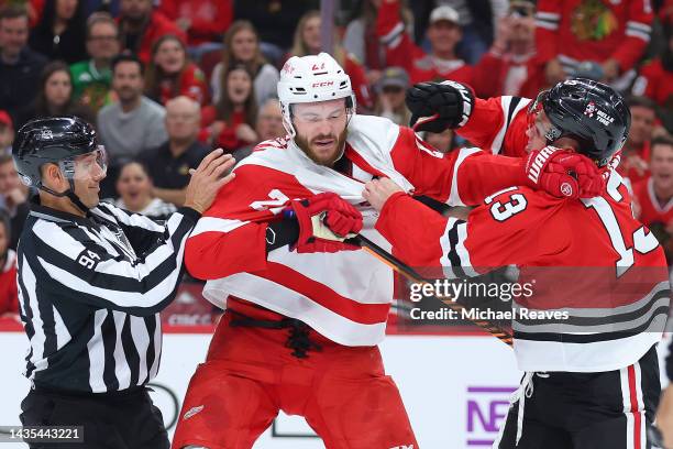 Michael Rasmussen of the Detroit Red Wings and Max Domi of the Chicago Blackhawks fight as linesman Bryan Pancich attempts to break it up during the...