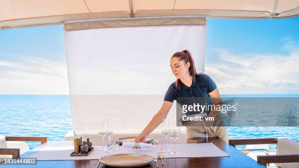 woman setting table before serving food, crew member preparing lunch on yacht - yacht crew stock pictures, royalty-free photos & images