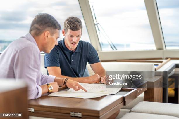 men sitting at table and discussing document - yacht crew stock pictures, royalty-free photos & images