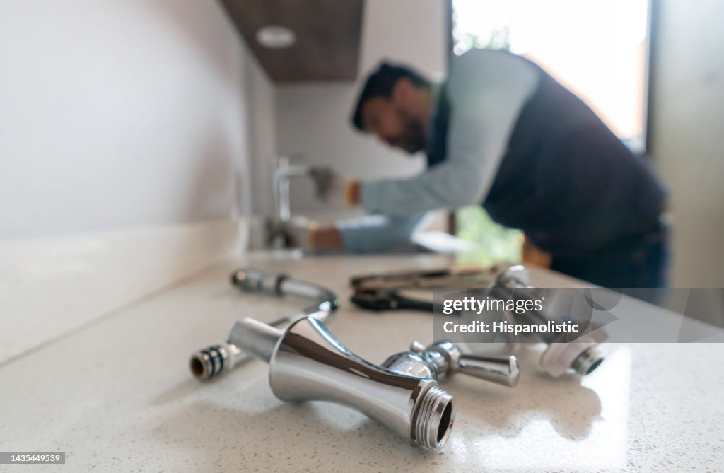 Plumber fixing a leak in the kitchen sink of a house