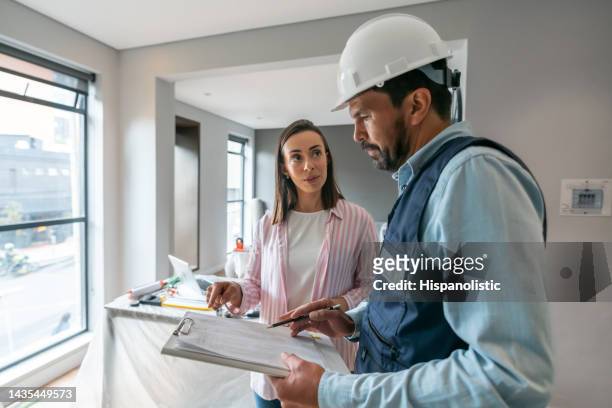 mujer hablando con un contratista mientras remodela su casa - building contractor fotografías e imágenes de stock