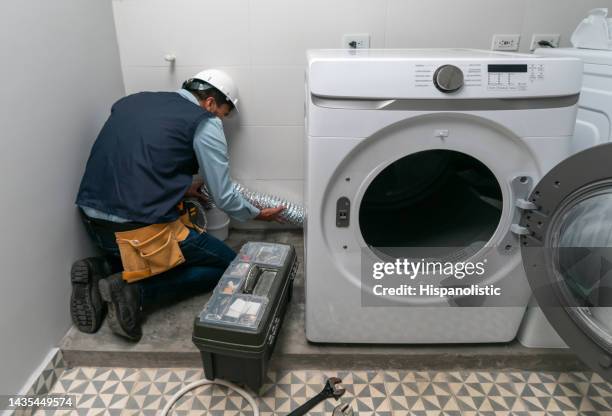 réparateur installant une machine à laver dans une maison - buanderie photos et images de collection