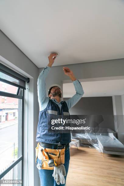 handyman changing a light bulb while working on a house renovation - broken light bulb stock pictures, royalty-free photos & images