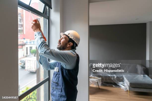 repairman fixing a leak on a window at an apartment - silicone 個照片及圖片檔