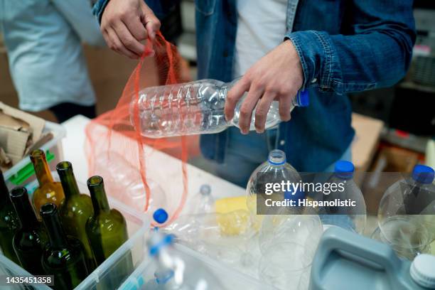 unrecognizable volunteers at a recycling centre separating recyclable material into different bags and containers - circular economy stock pictures, royalty-free photos & images