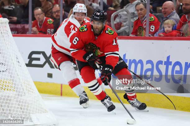 Jujhar Khaira of the Chicago Blackhawks skates with the puck defended by Lucas Raymond of the Detroit Red Wings during the second period at United...