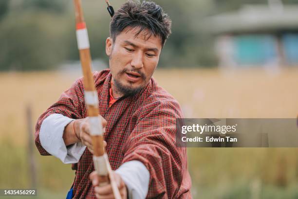 bhutanese man preparing in archery field - archer style stock pictures, royalty-free photos & images