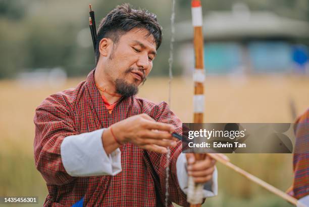 bhutanese man preparing in archery field - archer style stock pictures, royalty-free photos & images