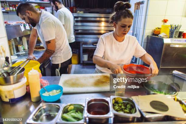 people working in kitchen in fast food restaurant and preparing food for delivery - pizza ingredients stock pictures, royalty-free photos & images