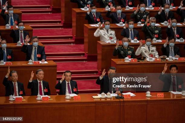 Chinese President Xi Jinping, centre, and Premier Li Keqiang raise their hands as they vote during the closing session of the 20th National Congress...