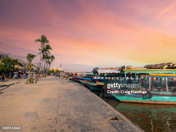 hoi an, vietnam - street and river water front scene of the beautiful uniform yellow houses, apartments, shops and restaurants of the famous tourist town. tranquil and idyllic landscape. - hoi an stockfoto's en -beelden