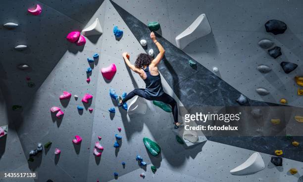 sportlerin trainiert klettern an indoor-kletterwand - sport stock-fotos und bilder