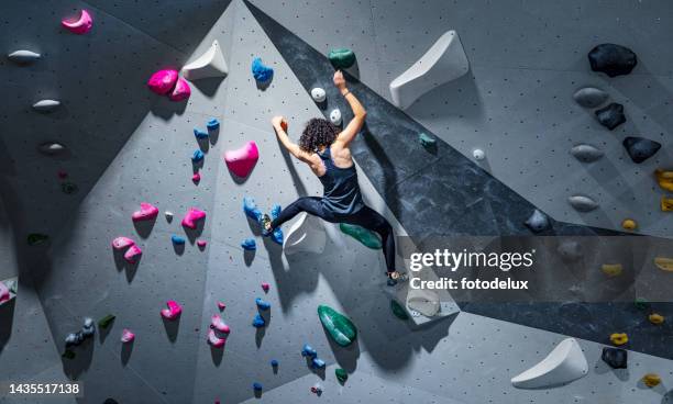 sportswoman training climbing on indoor climbing wall - escalar sem corda imagens e fotografias de stock