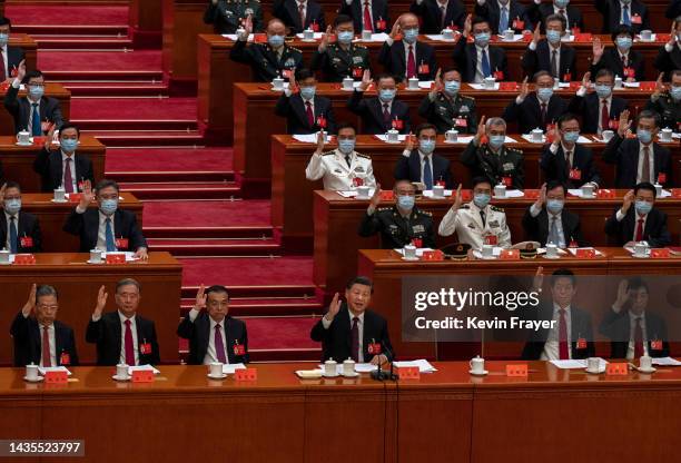 Chinese President Xi Jinping, centre bottom, and Premier Li Keqiang, centre left, and other senior members of the government raise their hands to...