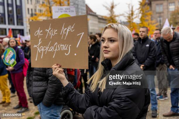 Protester holds a sign that reads "The crisis is called capitalism" as people march to demand a continued shift to renewable energy sources and...