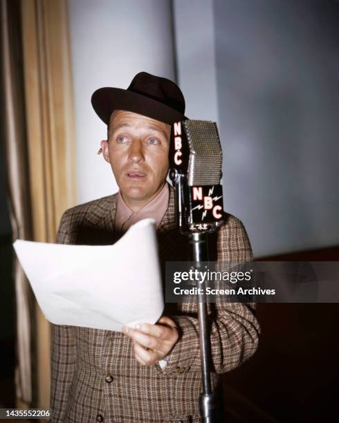 Bing Crosby color image of the American singer and actor reading script for NBC Radio Show circa 1945.