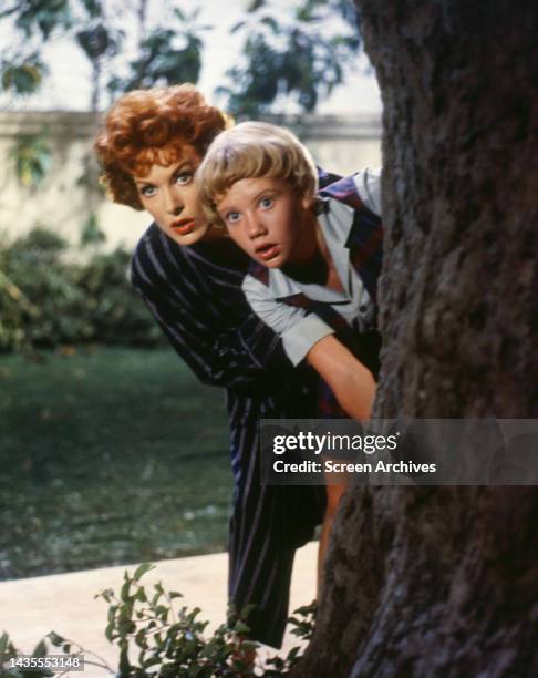 The Parent Trap Hayley Mills and Maureen O'Hara peeking from behind tree in a scene from the 1961 Walt Disney comedy.
