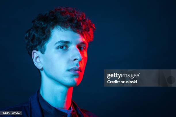 retrato de estudio en primer plano de un joven blanco con una chaqueta azul sobre fondo negro - man blue background fotografías e imágenes de stock