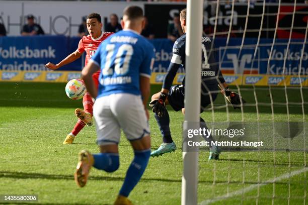 Jamal Musiala of Bayern Munich scores their team's first goal past Oliver Baumann of TSG 1899 Hoffenheim during the Bundesliga match between TSG...