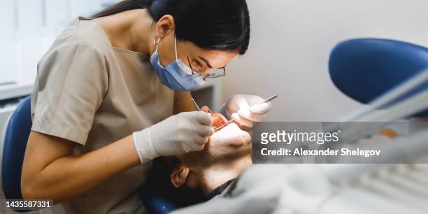 group portrait of two people, woman dentist making treatment in modern clinic for man. medical concept photography indoors for dentistry. dental office, doctor working in clinic with patient. - tandläkare bildbanksfoton och bilder