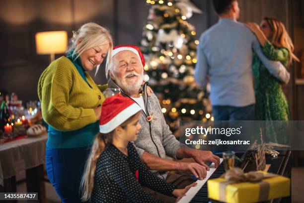 multigeneration family gathering for christmas celebration and playing on piano - carol singer stock pictures, royalty-free photos & images