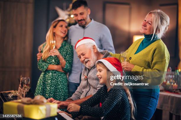 multigeneration family gathering for christmas celebration and playing on piano - carol singer stock pictures, royalty-free photos & images