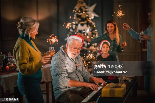 multigeneration family gathering for christmas celebration and playing on piano - carol singer stock pictures, royalty-free photos & images