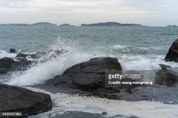 the waves crash on the black reef - littoral rocheux photos et images de collection