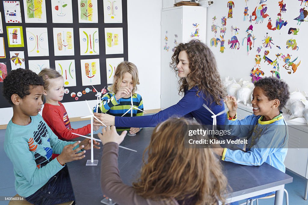 Teacher with children playing with wind turbines