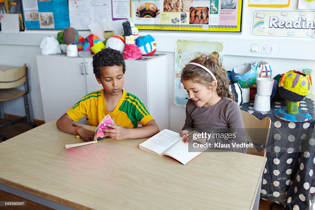 2 kids looking in books at school