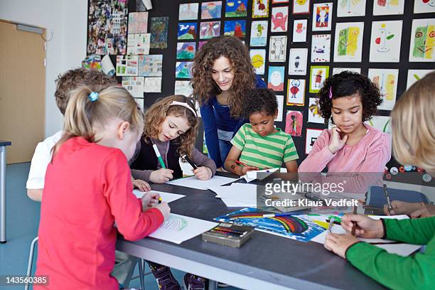 teacher together with kids drawing in classroom - bambini seduti in cerchio foto e immagini stock