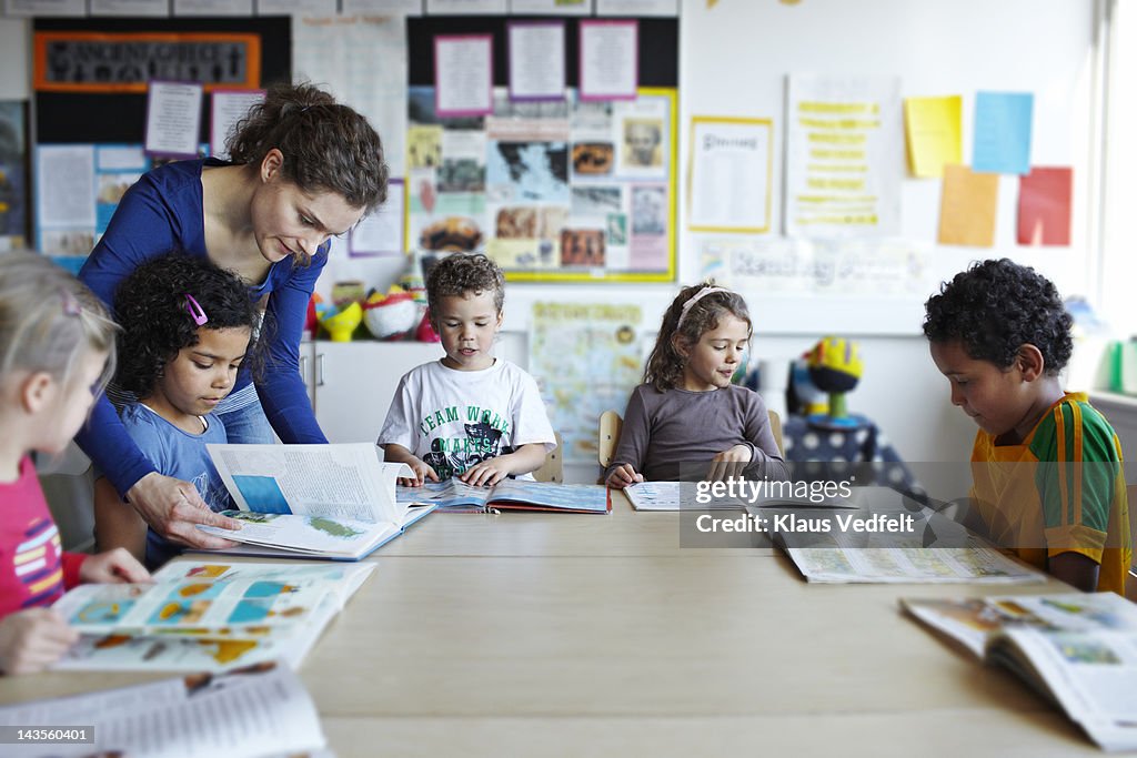 Teacher looking in books with children